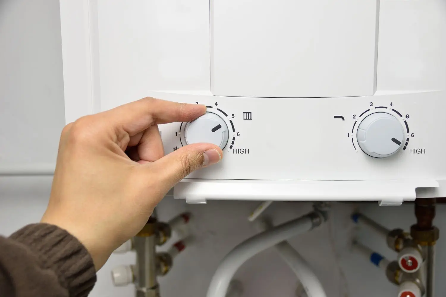 A hand turning the temperature dial on a water heater