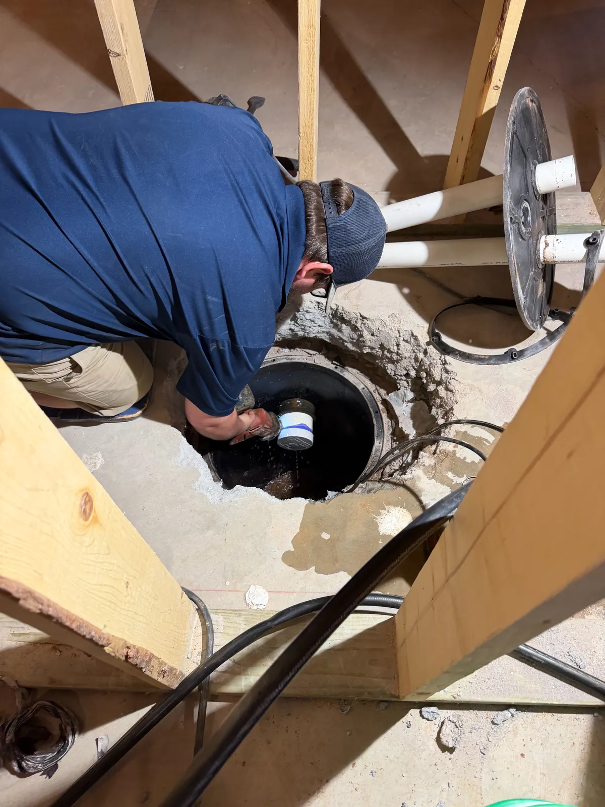 A Smith Plumbing technician working in a pit under a house